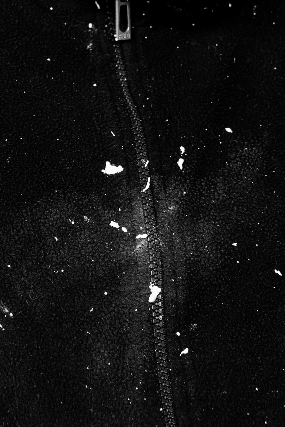 The front of a dark sweatshirt, divided by a vertical zipper.
Plaster dust strikes across the fabric in sharp, scattered marks.
It is Davide Rivalta, the artist behind the iconic lions standing in front of the Galleria Nazionale in Rome.