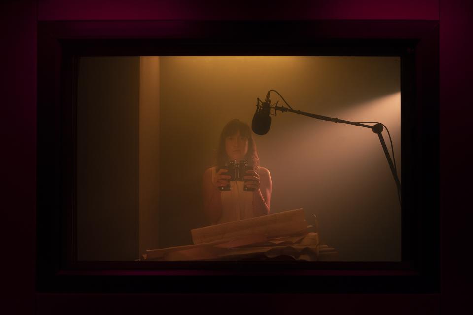 Red light frames the glass.
The booth never changes.
Same microphone. Same walls. Same air.
But each podcast reshapes the room into a different world.
Here, binoculars in hand — a travel podcast begins.
HYPERCAST — one space, infinite journeys.